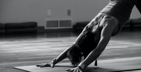 woman in black tank top and black pants bending her body on floor