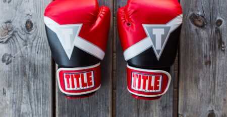 pair of red-and-black Title training gloves on grey wooden plank