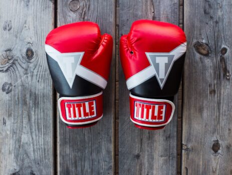 pair of red-and-black Title training gloves on grey wooden plank